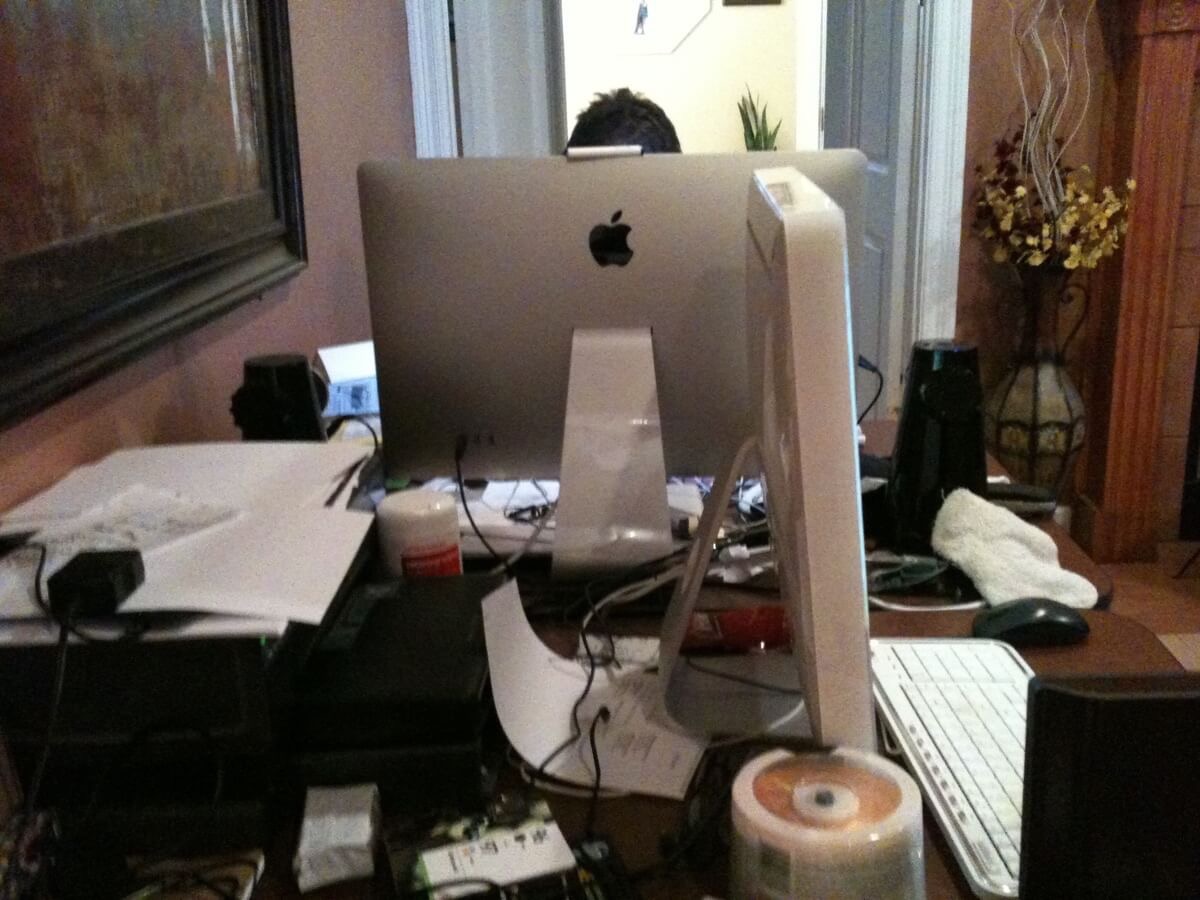 A very messy pair of tables in the living room, each with a Mac. The top of my head is just visible above my Apple Cinema Display.